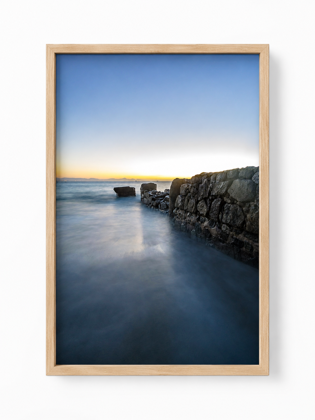 Umbral del Amanecer fotografía vertical de paisaje marítimo al amanecer enmarcada con marco de madera natural clara sobre fondo blanco